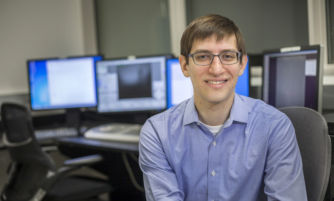 greg alushin sits in a chair in front of computers